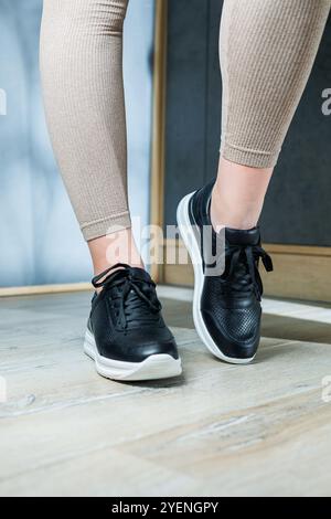 Kollektion von Damenschuhen. Schwarze Lederschuhe an den Füßen von Frauen. Weibliche Füße in bequemen, legeren Sandalen Stockfoto