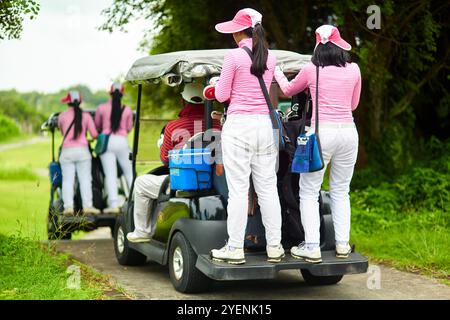 Frauen, die auf Golfwagen stehen, während sie sich bewegen. Bali, Indonesien - 24.03.2018 Stockfoto