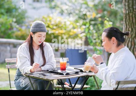Ein koreanischer Mann und eine Japanerin, beide im Alter von 30 Jahren und ein verheiratetes Paar, genießen in einem stilvollen Café im Herbst einen Brunch mit drei Hunden Stockfoto