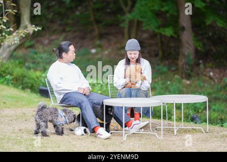 Ein koreanischer Mann und eine Japanerin, beide im Alter von 30 Jahren und ein verheiratetes Paar, genießen in einem stilvollen Café im Herbst einen Brunch mit drei Hunden Stockfoto