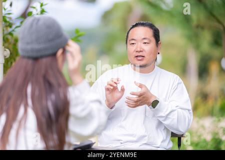 Ein koreanischer Mann und eine Japanerin, beide im Alter von 30 Jahren und ein verheiratetes Paar, genießen in einem stilvollen Café im Herbst einen Brunch mit drei Hunden Stockfoto
