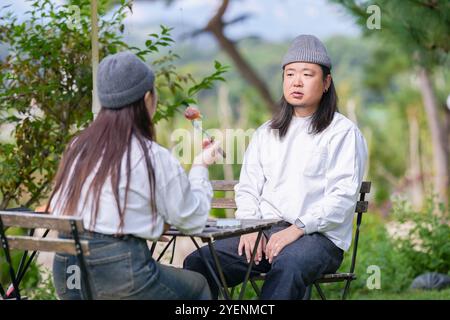 Ein koreanischer Mann und eine Japanerin, beide im Alter von 30 Jahren und ein verheiratetes Paar, genießen in einem stilvollen Café im Herbst einen Brunch mit drei Hunden Stockfoto