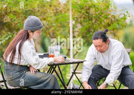 Ein koreanischer Mann und eine Japanerin, beide im Alter von 30 Jahren und ein verheiratetes Paar, genießen in einem stilvollen Café im Herbst einen Brunch mit drei Hunden Stockfoto