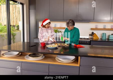 weihnachtskekse dekorieren, ältere Freundinnen lächeln fröhlich zu Hause. Backen, festlich, Urlaub, kulinarisch, Freundschaft, Tradition Stockfoto