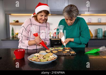 In der gemütlichen Küche dekorieren ältere Freundinnen Weihnachtskekse, teilen Urlaubsgeist, zu Hause. Festlich, backen, Lebensstil, Zweisamkeit, Freude, f Stockfoto