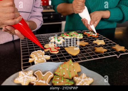 Ältere Freunde schmücken zusammen Weihnachtskekse, teilen festliche Backaktivitäten, zu Hause. Feiertage, Feier, Freundschaft, Tradition, kulinarisches, Stockfoto