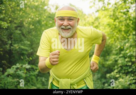 Lächelnder, glücklicher älterer Mann, der rennt. Senior Mann macht Sport im Freien. Seniorentraining im Rehabilitationszentrum. Alte und junge Sportler Stockfoto
