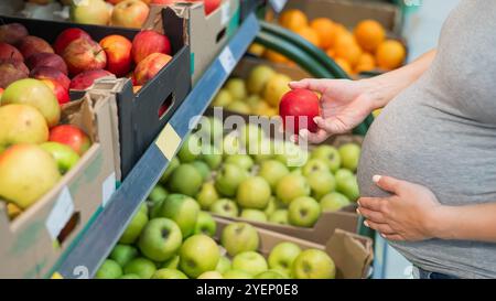 Schwangere Frau wählt Äpfel im Laden. Stockfoto