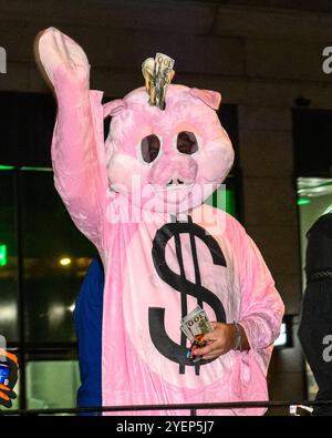 New York, USA. 31. Oktober 2024. Eine Person in Schweineverkleidung wirft während der 51. Jährlichen Halloween-Parade im Manhattan Greenwich Village gefälschte 100-Dollar-Banknoten aus einem Wagen. Quelle: Enrique Shore/Alamy Live News Stockfoto