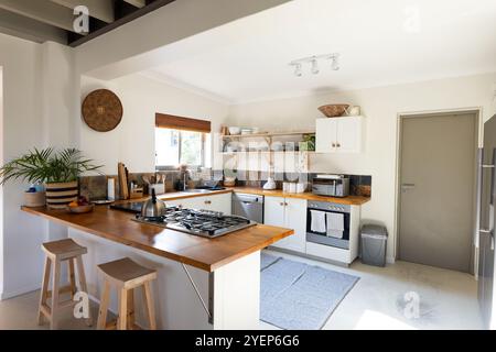Moderne Küche mit Holzarbeitsplatten und Hockern, heller und einladender Raum, zu Hause. Interior, Design, Möbel, modern, Dekor, Startseite Stockfoto