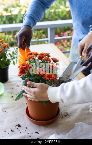 Pflanzen von Blumen auf der Veranda, multirassische Paare, die zusammen im Garten arbeiten, teilen Outdoor-Aktivitäten. Hobby, Teamarbeit, Freizeit Stockfoto