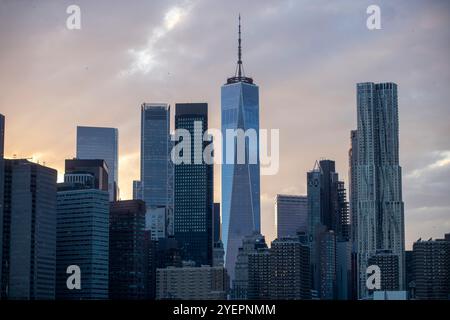 Dieses Bild zeigt die legendäre Skyline von New York City, die das One World Trade Center vor einem dramatischen Himmel bei Sonnenuntergang zeigt. Stockfoto