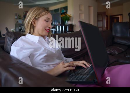 Geschäftsfrau, die auf einem Sofa mit Laptop relaxt Stockfoto