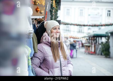 Frau in hellvioletter Jacke, die den Weihnachtsmarkt im Freien genießt Stockfoto