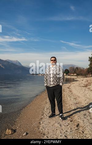 Schöner junger Mann, der am Strand steht Stockfoto