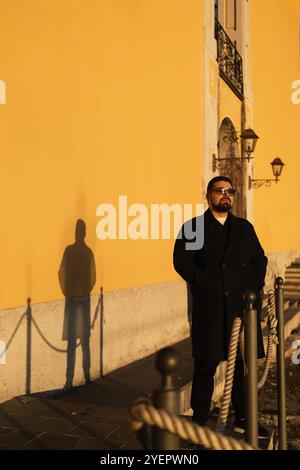 Porträt eines jungen, gutaussehenden Mannes mit seinem Schatten auf der gelben Wand Stockfoto