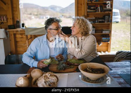 Ein Paar mittleren Alters riecht zu Hause nach frischen Kräutern. Stockfoto