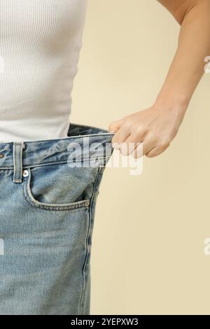 Studio-Aufnahme einer jungen kaukasischen Frau, die nach der Diät große Jeans trägt Stockfoto