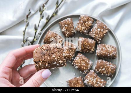 Weibliche Hand halten Haferkekse, Haferdaten Energie, selektiver Fokus. Vegane Süßigkeiten. Hausgemachte Bäckerei. Rohes veganes gesundes Dessert aus Datteln und Nüssen. Gl Stockfoto