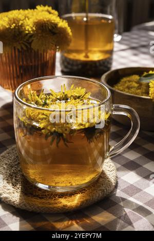 Löwenzahnblume gesunder Tee in Glas Teekanne und Glasbecher auf dem Tisch. Köstlicher Kräutertee aus frischen Löwenzahnblumen zu Hause am Sommertag. Grüne Kl Stockfoto