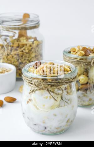 Gesundes Frühstück. Haferflockengranola mit griechischem Joghurt und Nüssen Bananenmüsli in Gläsern auf hellem Hintergrund. Vegan, vegetarisch und Gewichtsverlust Ernährung concep Stockfoto