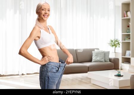 Glückliche, schlanke Frau, die zu Hause eine Jeans anzieht Stockfoto