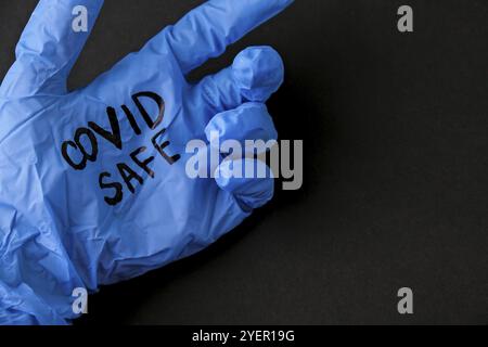 Aufgeblasene blaue Latex-OP-Handschuh auf schwarzem Hintergrund. Erneutes Öffnen von covid Safe. Öffnen Sie wieder Text auf medizinischen Handschuh geschrieben. Neuer Normalwert. Coronavirus outbre Stockfoto