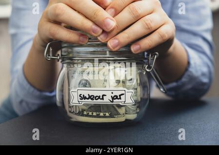 Weibliche Hände halten Glasgefäß voll mit US-Dollar-Banknote mit TEXTSCHWÖRUNG JAR. Vorbereitung spart Geld. Mäßiger Verbrauch und Stockfoto