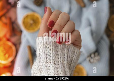 Frau gepflegte Hände, stilvolle rote Nägel, Copy Space. Blauer Pullover Closeup. Design-Konzept im Winter- oder Herbststil. Schönheitsbehandlung. Fallnagel Stockfoto