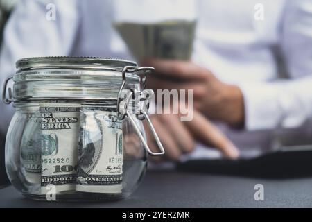 Der Mann übergibt Zählkosten Banknoten in Dollar-Bargeld auf den Rechner. Nahaufnahme von Händen, unerkennbarer Geschäftsmann. Investitionskonzept sparen. A Stockfoto