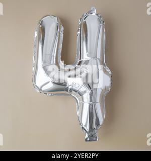 4 vier metallische Ballons auf beigefarbenem neutralen Hintergrund. Grußkarte Silberfolie Ballonnummer Happy Birthday Holiday Konzept. Kopierbereich für Text. Cel Stockfoto