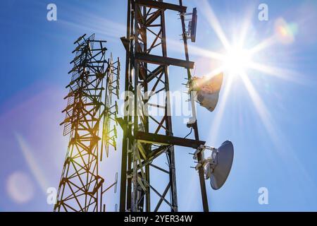 Helle Sonne über zwei mobilfunkmasten, Radio und GPS-Sender und Empfänger, mit elektromagnetischen Umweltverschmutzung, mit lebhaften lens flare Stockfoto
