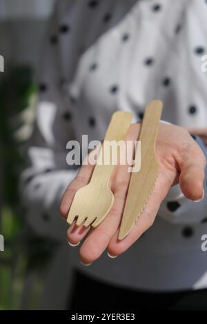 Weibliche Hände mit Holzgabeln und Pappbecher mit Tellern. Umweltfreundliches Einweggeschirr. Wird in Fast Food, Restaurants, Imbissbuden und Picknicks verwendet. N Stockfoto