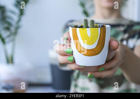 Nahaufnahme von weiblichen Händen, die Kakteen transplantieren. Hausgarten Konzept. Gartengeräte. Arbeitsplatz des Gärtners. Erde in einem Eimer. Pflege der Pflanzen. Stockfoto