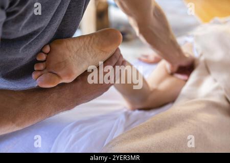 Junge Frauen genießen eine entspannende Beinmassage in gemütlicher häuslicher Umgebung. Frau, die im Spa-Center eine Beinmassage erhält. Beinmassage-Therapie Stockfoto