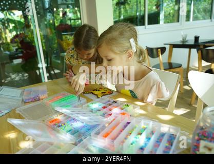 Die Lehrerin in der Werkstatt hat zwei Mädchen beigebracht, wie man ein Thermomosaik zusammenbaut Stockfoto