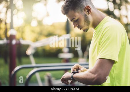 FIT Mann Check Smart Watch Wearable Technologie Sport Smartwatch beim Workout draußen. Mann, der während seines Trainings eine intelligente Uhr trägt, misst seine Aktivität Stockfoto