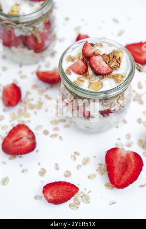 Gesundes Frühstück. Haferflockengranola mit griechischem Joghurt und Nüssen Erdbeermüsli in Gläsern auf hellem Hintergrund. Vegan, vegetarisch und weight Loss diet Co Stockfoto