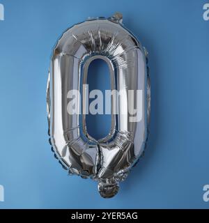 0 0 metallischer Ballon auf blauem Hintergrund isoliert. Grußkarte Silberfolie Ballonnummer Happy Birthday Holiday Konzept. Kopierbereich für Text. Cel Stockfoto