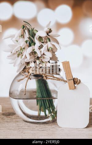 Bouquet von Schneeglöckchen in einer Glasvase mit Wasser. Platz für Text kopieren. Mit einem Anhänger nachmachen. Frühe Frühlingsblumen. Weihnachtskarte Stockfoto