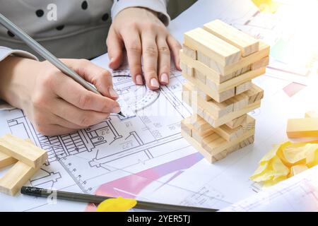 Architekt Designer Interior kreative Arbeit Hand spielen ein Block Holz Spiel auf dem Schreibtisch architektonischen Plan des Hauses, eine Farbpalette. Architektin Stockfoto