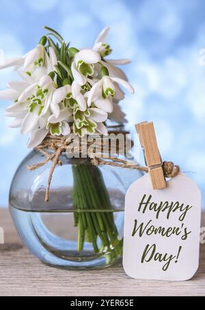 Grußkarte mit Schriftzug „Happy Womens Day“. Frühlingsblumen Schneeglöß. Schöner zarter Blumenstrauß. Urlaubskonzept. Kreativ modern Stockfoto