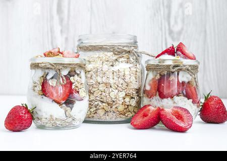 Gesundes Frühstück. Haferflockengranola mit griechischem Joghurt und Nüssen Erdbeermüsli in Gläsern auf hellem Hintergrund. Vegan, vegetarisch und weight Loss diet Co Stockfoto