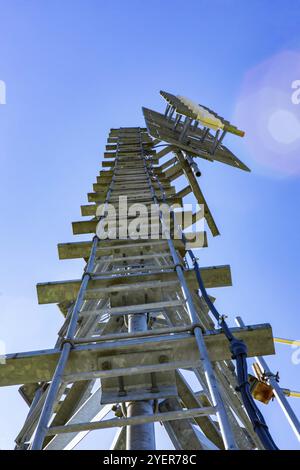 Ein Würmer aus der Sicht ein hohes Mobilfunk Basisstation Turm gegen einen blauen Himmel mit Kopie Raum über. Radio Transmission Mast von unten mit stahlleiter Stockfoto