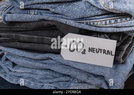 CO2-neutraler Emissions-Textnotiz auf dem Jeansstapel. Umweltfreundlich, Klimaschutz, umweltfreundlicher Kraftstoff und Schutzkonzept für die Erde. CO2-Emissionspapier Stockfoto