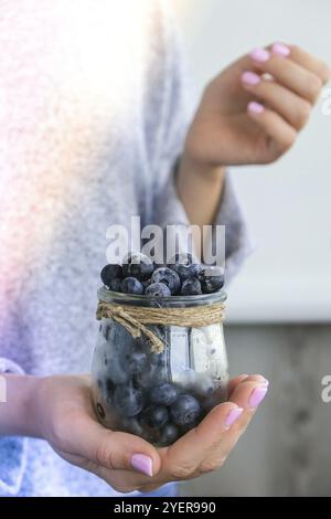 Frau hält eine Schüssel mit gefrorenen Heidelbeerfrüchten. Erntekonzept. Weibliche Hände sammeln Beeren. Gesunde Ernährung Konzept. Auffüllen von Beeren für Stockfoto