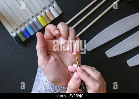 Arbeiten Sie zu Hause mit Nägeln. Nagelpflege, Selbstpflege. Maniküre für Frauen. Machen Sie Maniküre selbst, während Sie zu Hause bleiben. Frau weibliche Hände, Maniküre Werkzeuge Stockfoto