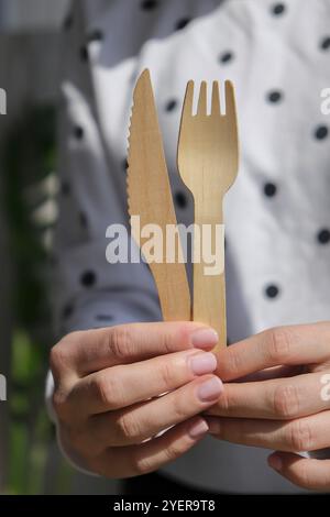 Weibliche Hände mit Holzgabeln und Pappbecher mit Tellern. Umweltfreundliches Einweggeschirr. Wird in Fast Food, Restaurants, Imbissbuden und Picknicks verwendet. N Stockfoto