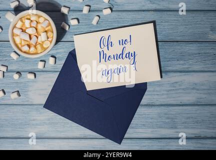 OH NEIN MONDAY AGAIN Konzepttext blauer Umschlag mit weißer Tasse Kaffee und Marshmallows auf hölzernem Hintergrund. Der deprimierendste Tag des Jahres in J Stockfoto