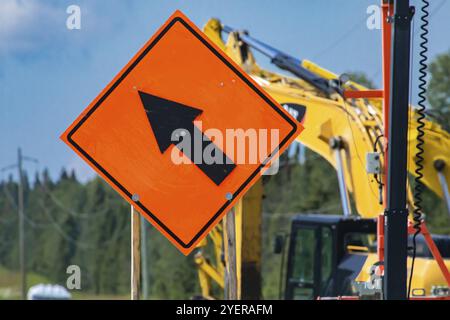 Temporärer Zustand Verkehrszeichen, Geschlossen Lane. Geschwindigkeit einstellen mit dem Verkehr in der Spur durch den Pfeil nach links, Bagger im Hintergrund gekennzeichnet zusammenführen Stockfoto